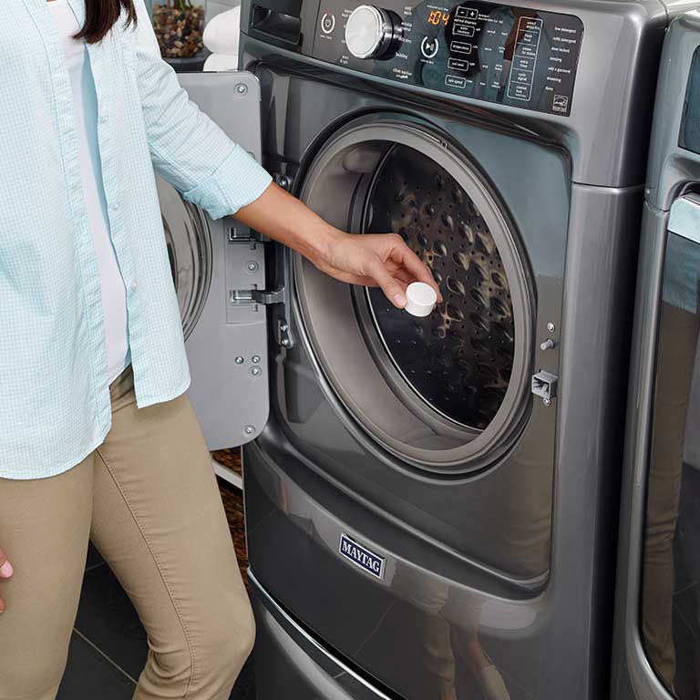 Une femme place une pastille affresh® dans une laveuse